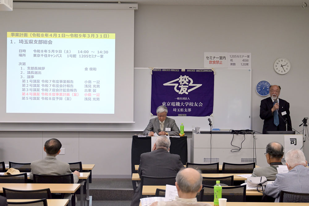 総会・議長と事業計画を説明する小島副支部